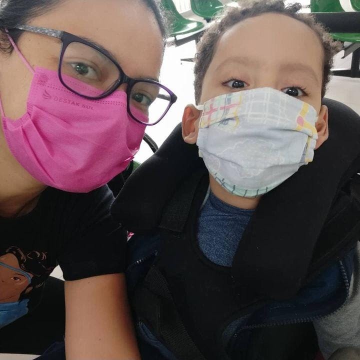 Nathalia e Matias (Mãe e filho) posando para foto selfie. Ambos usam máscara. Nathalia usa óculos de grau.